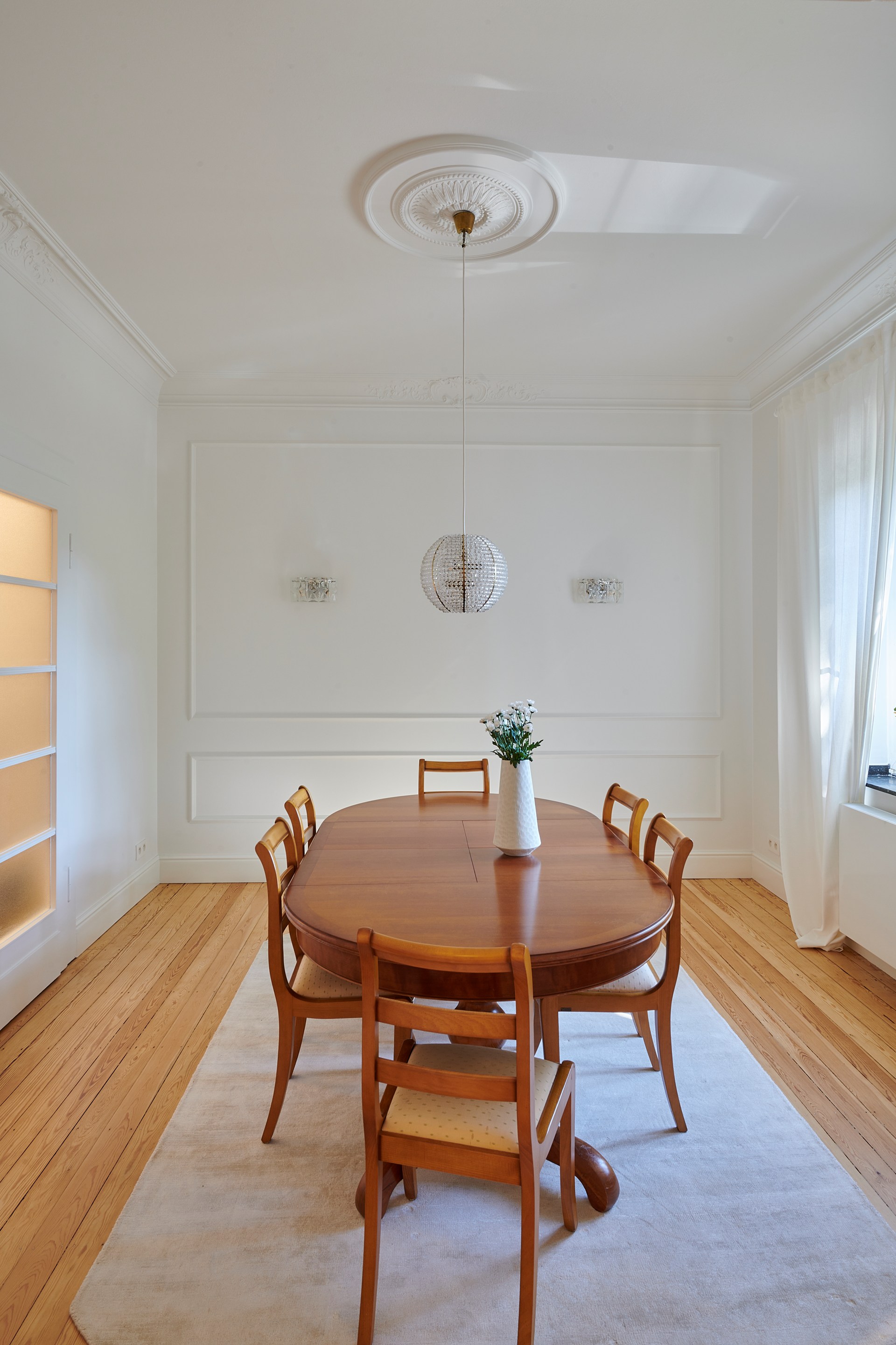 Dekorative Rosette und Zierleisten, die ein elegantes Esszimmer mit Pendelleuchten aufwerten.