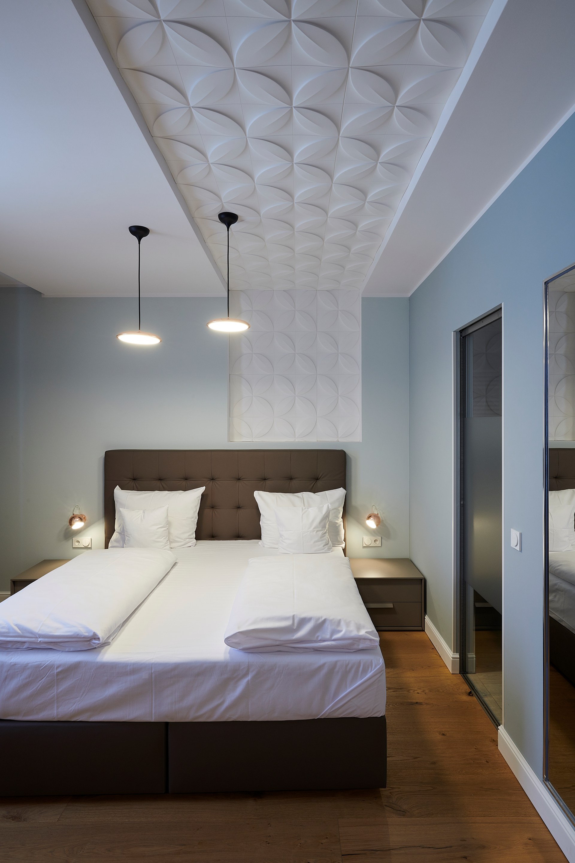 Dekorative Wandpaneele an der Decke schaffen eine strukturierte Deckenoptik über dem Bett.