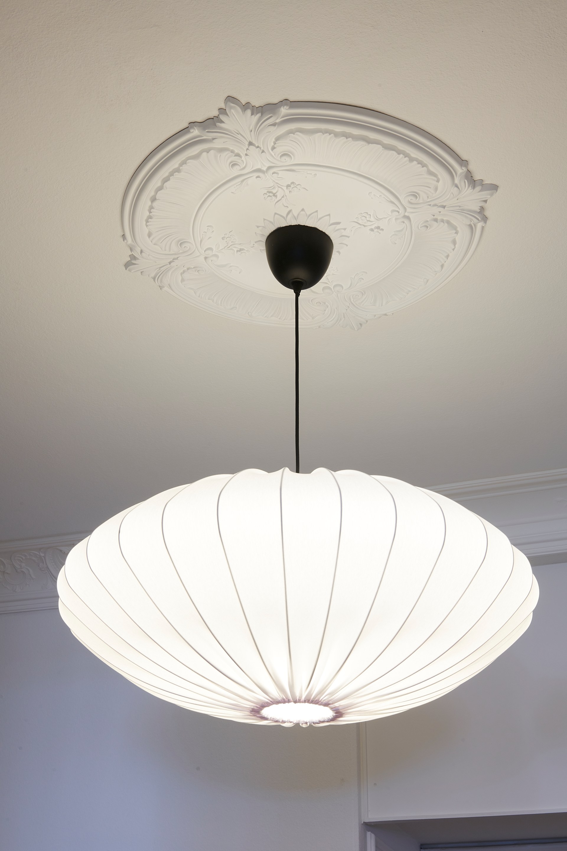 Verzierte Rosette mit skulpturalen Details unterstreicht die klassische Deckendekoration.